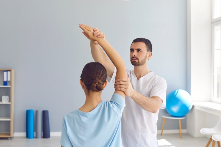 Young male osteopath masseur in white clothes kneads the joints of the girl's hand